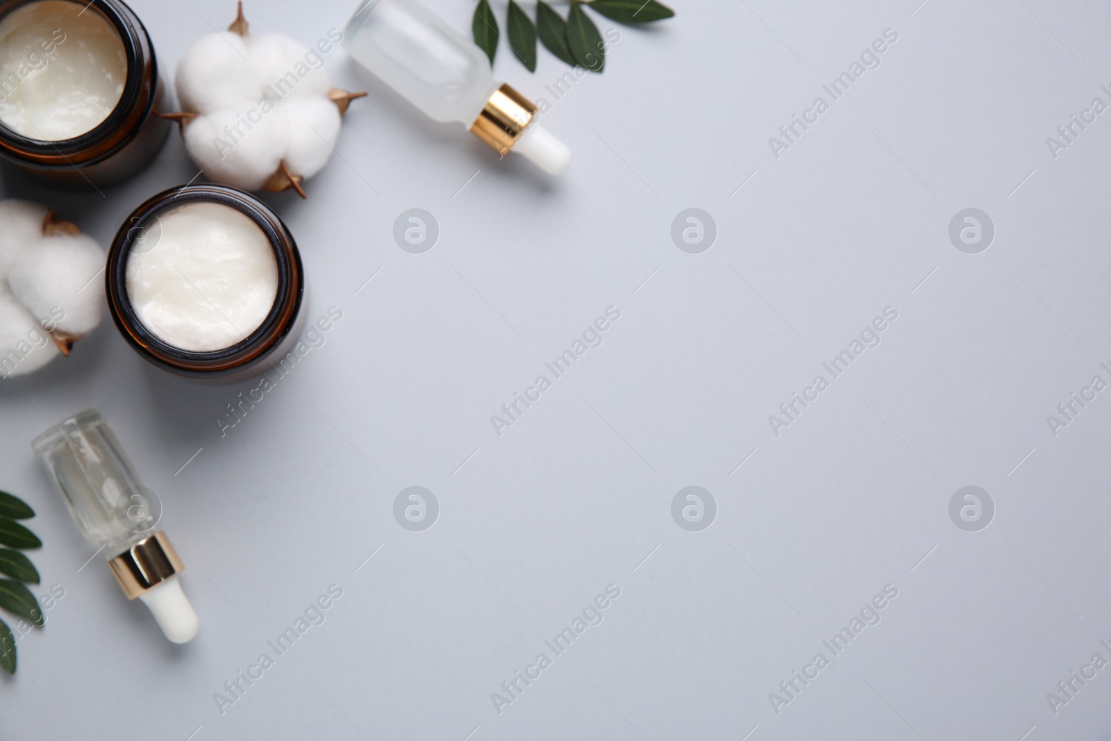 Photo of Different cosmetic products, leaves and cotton flowers on grey background, flat lay. Space for text