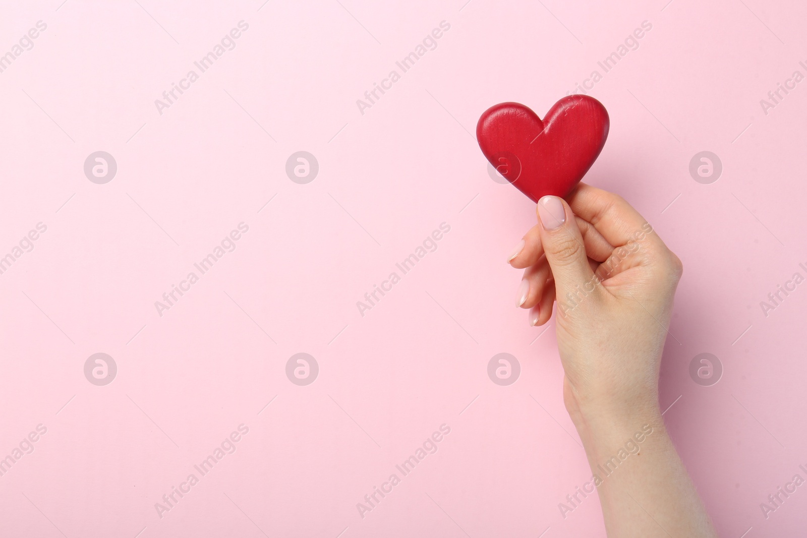 Photo of Woman holding red heart on pink background, top view. Space for text