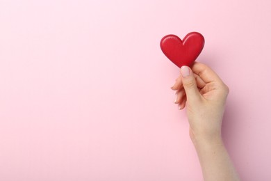 Photo of Woman holding red heart on pink background, top view. Space for text