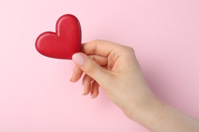 Photo of Woman holding red heart on pink background, top view