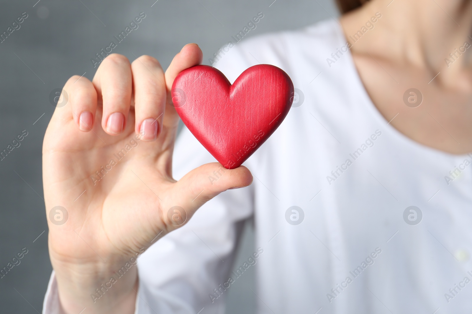 Photo of Doctor holding red heart on grey background, closeup