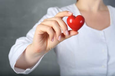 Photo of Doctor holding red heart on grey background, closeup