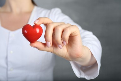 Photo of Doctor holding red heart on grey background, closeup