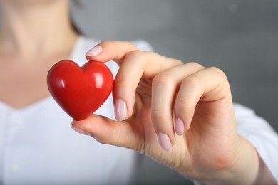 Photo of Doctor holding red heart on grey background, closeup