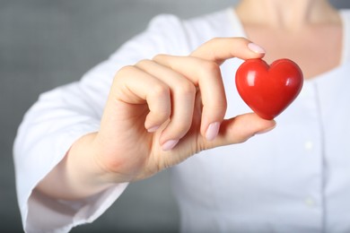 Photo of Doctor holding red heart on grey background, closeup