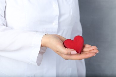 Photo of Doctor holding red heart on grey background, closeup