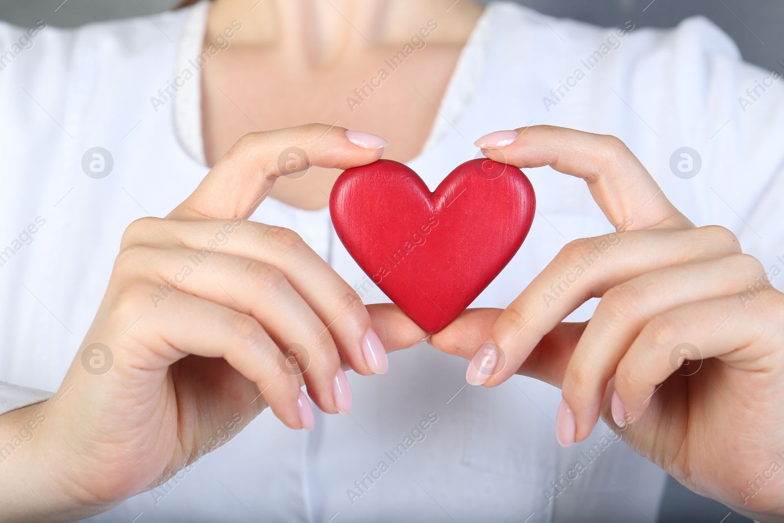 Photo of Doctor holding red heart on grey background, closeup