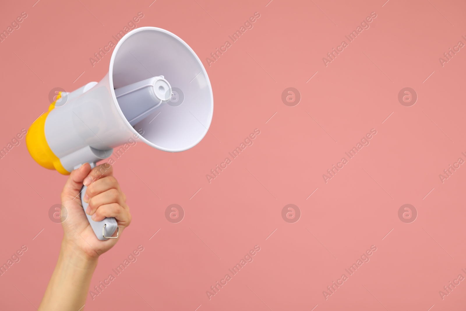 Photo of Woman holding megaphone speaker on pink background, closeup. Space for text