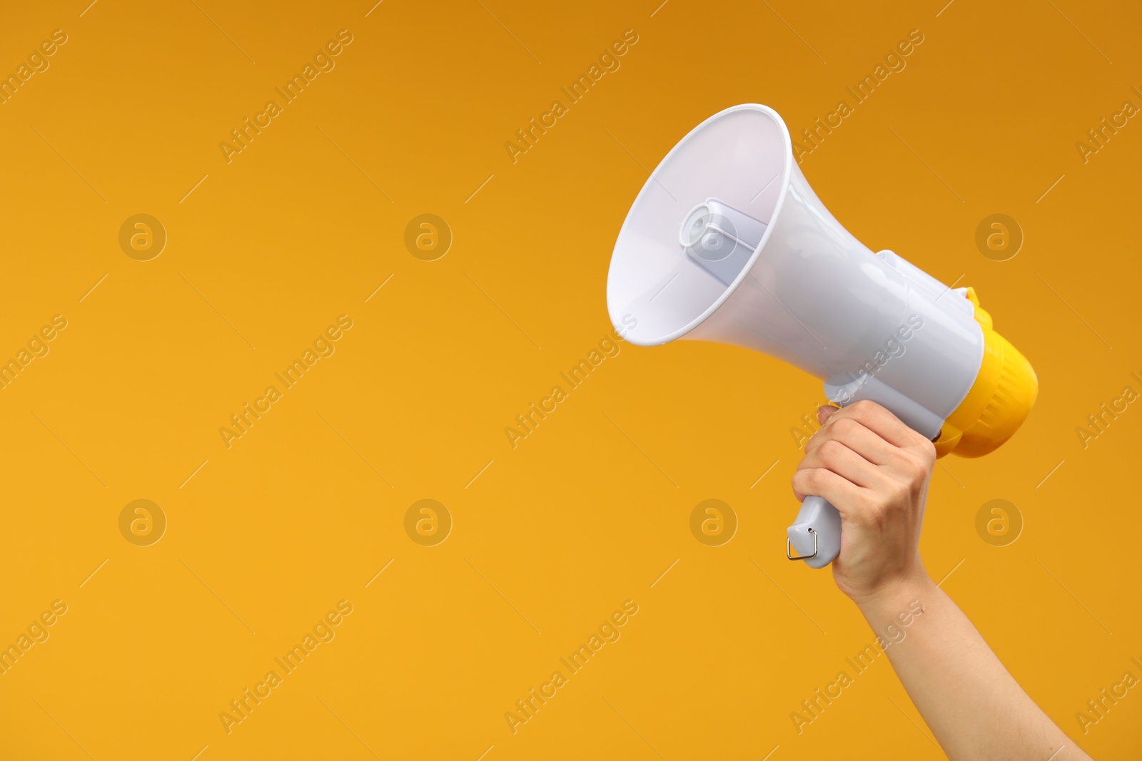 Photo of Woman holding megaphone speaker on orange background, closeup. Space for text