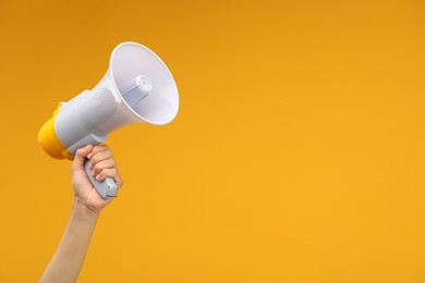 Photo of Woman holding megaphone speaker on orange background, closeup. Space for text