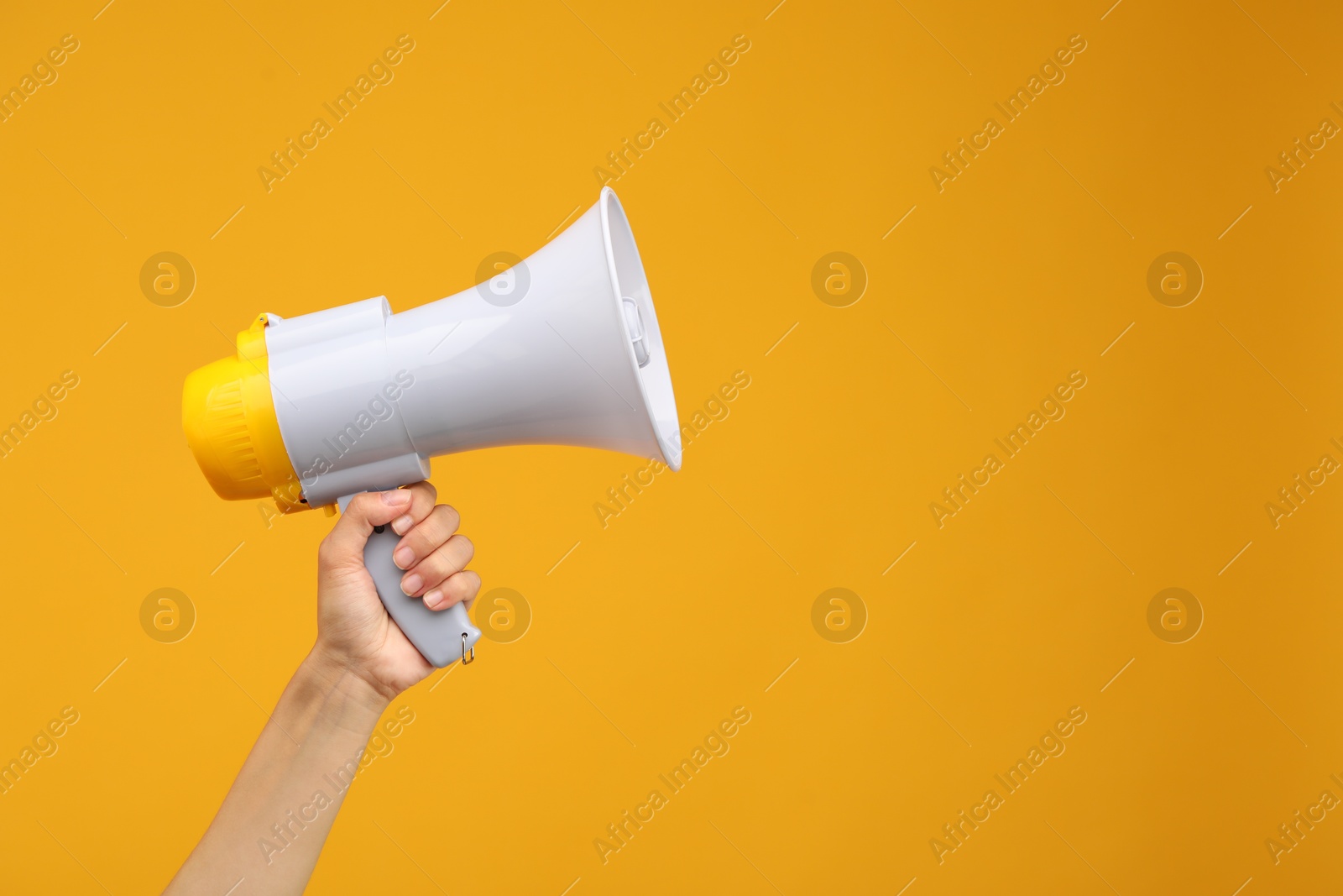 Photo of Woman holding megaphone speaker on orange background, closeup. Space for text