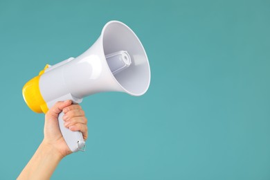 Woman holding megaphone speaker on blue background, closeup. Space for text