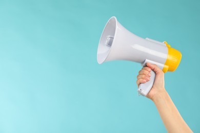 Woman holding megaphone speaker on blue background, closeup. Space for text