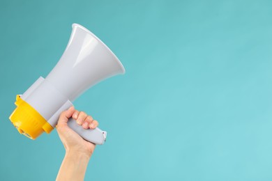 Woman holding megaphone speaker on blue background, closeup. Space for text