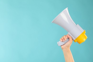 Woman holding megaphone speaker on blue background, closeup. Space for text