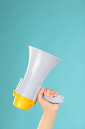 Photo of Woman holding megaphone speaker on blue background, closeup