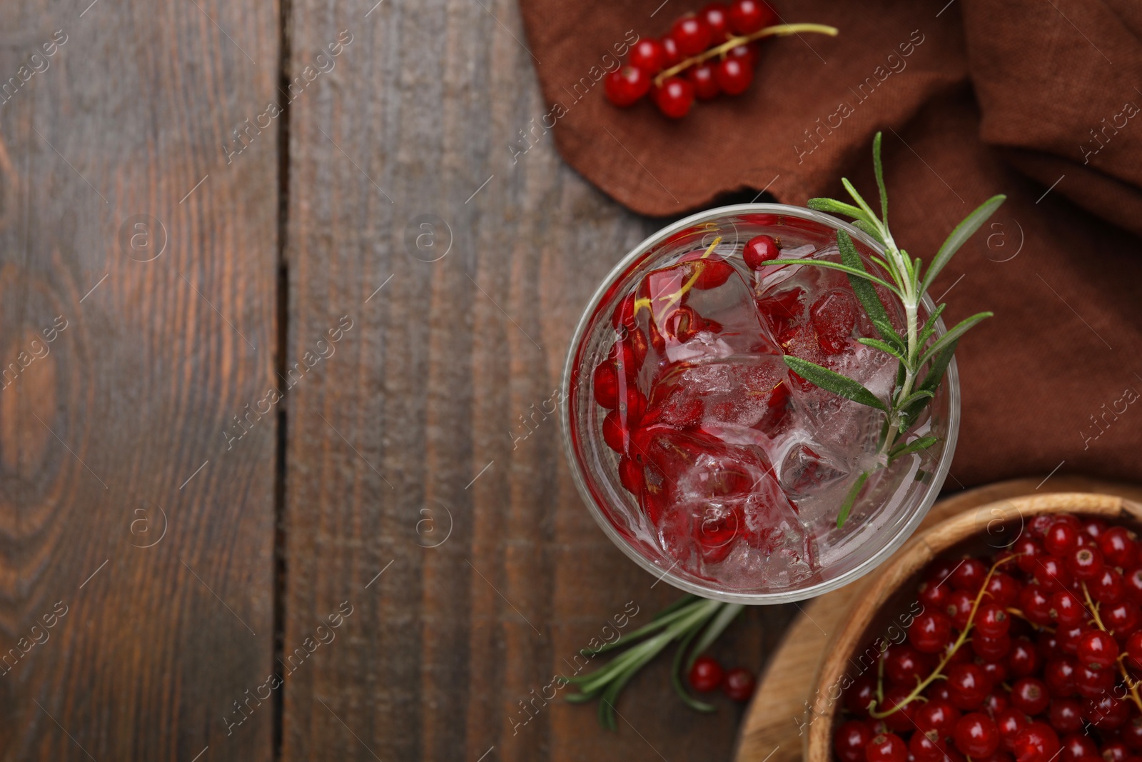 Photo of Refreshing water with red currants and rosemary in glass on wooden table, flat lay. Space for text