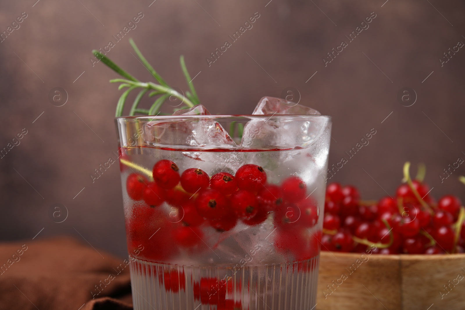 Photo of Refreshing water with red currants and rosemary in glass on table, closeup