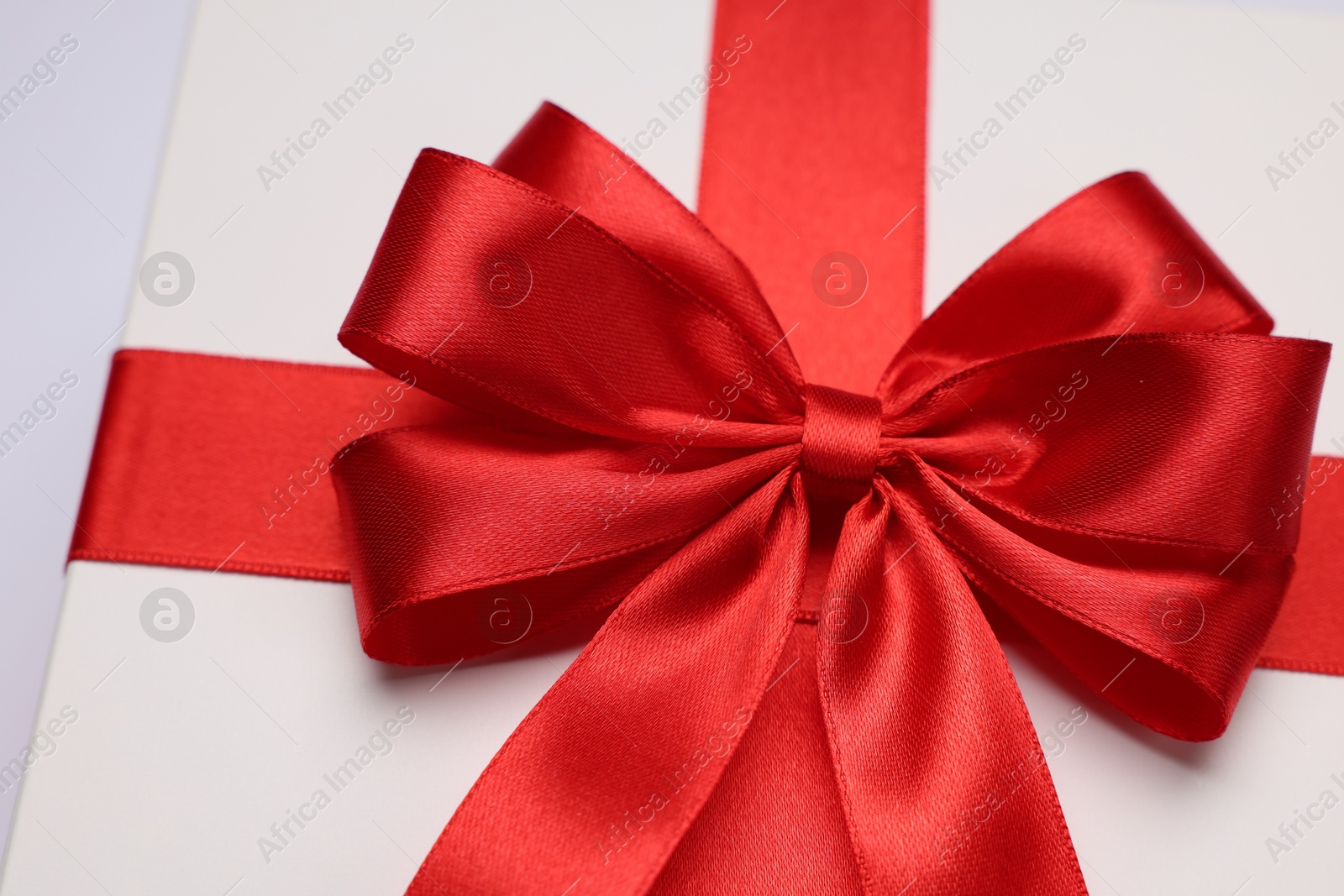 Photo of Gift box with red bow on light grey background, closeup