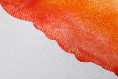 Orange watercolor painting on white paper, top view. Space for text