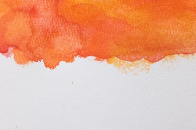 Photo of Orange watercolor painting on white paper, top view. Space for text