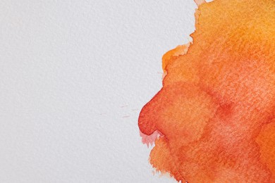 Photo of Orange watercolor painting on white paper, top view. Space for text