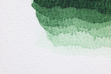 Photo of Green watercolor painting on white paper, top view