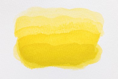 Yellow watercolor painting on white paper, top view