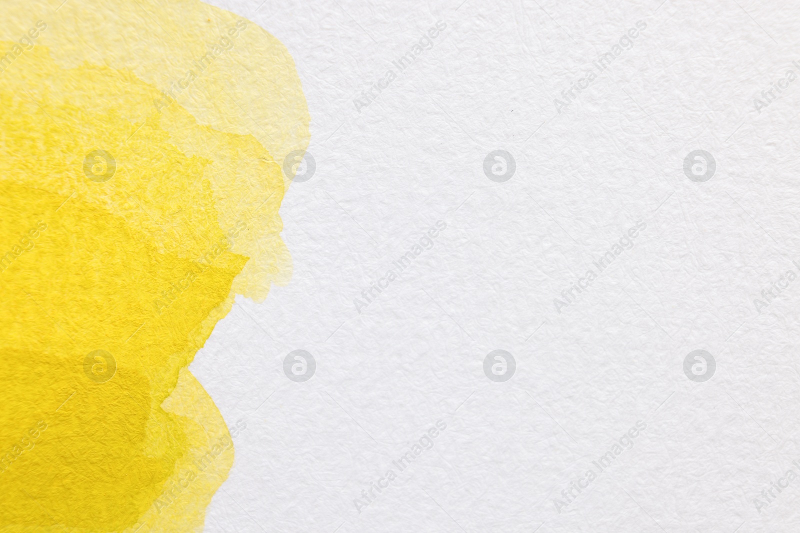 Photo of Yellow watercolor painting on white paper, top view. Space for text