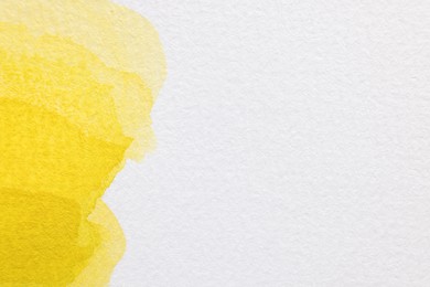 Yellow watercolor painting on white paper, top view. Space for text