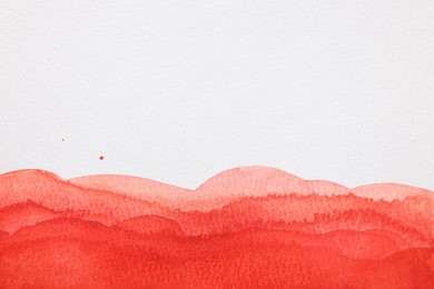 Red watercolor painting on white paper, top view. Space for text