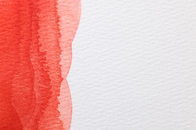 Photo of Red watercolor painting on white paper, top view. Space for text