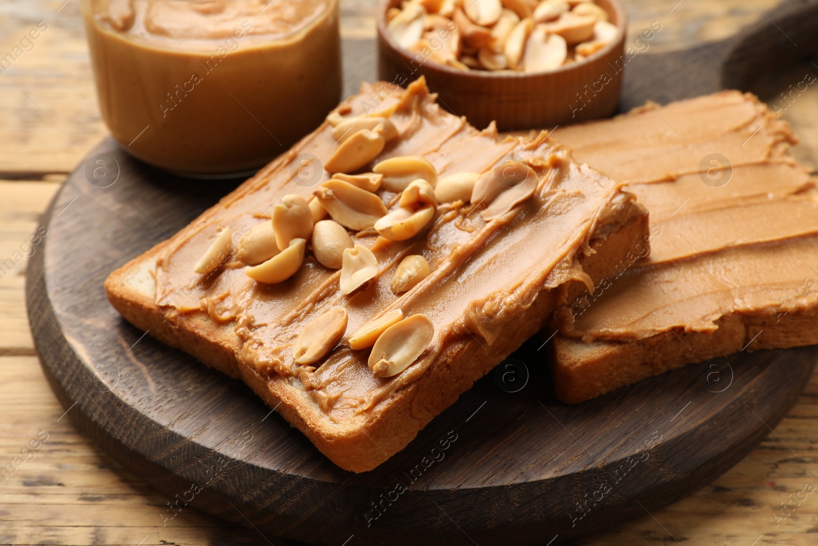 Photo of Delicious sandwiches with peanut butter and fresh nuts on wooden table, closeup