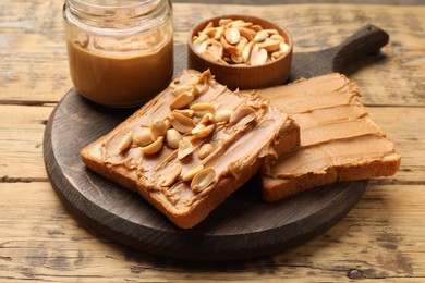 Photo of Delicious sandwiches with peanut butter and fresh nuts on wooden table, closeup