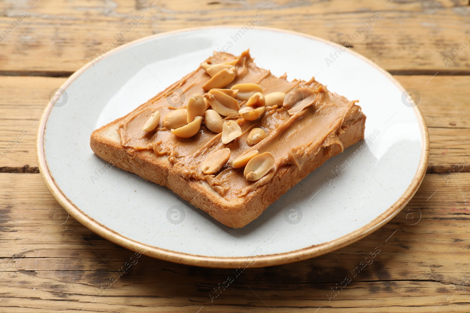 Photo of Delicious sandwich with peanut butter and fresh nuts on wooden table, closeup