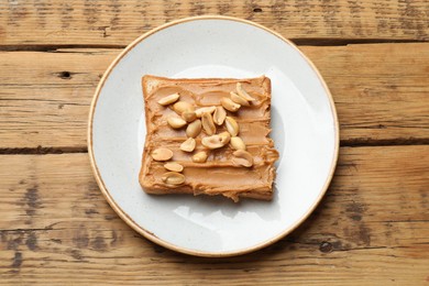 Photo of Delicious sandwich with peanut butter and fresh nuts on wooden table, top view