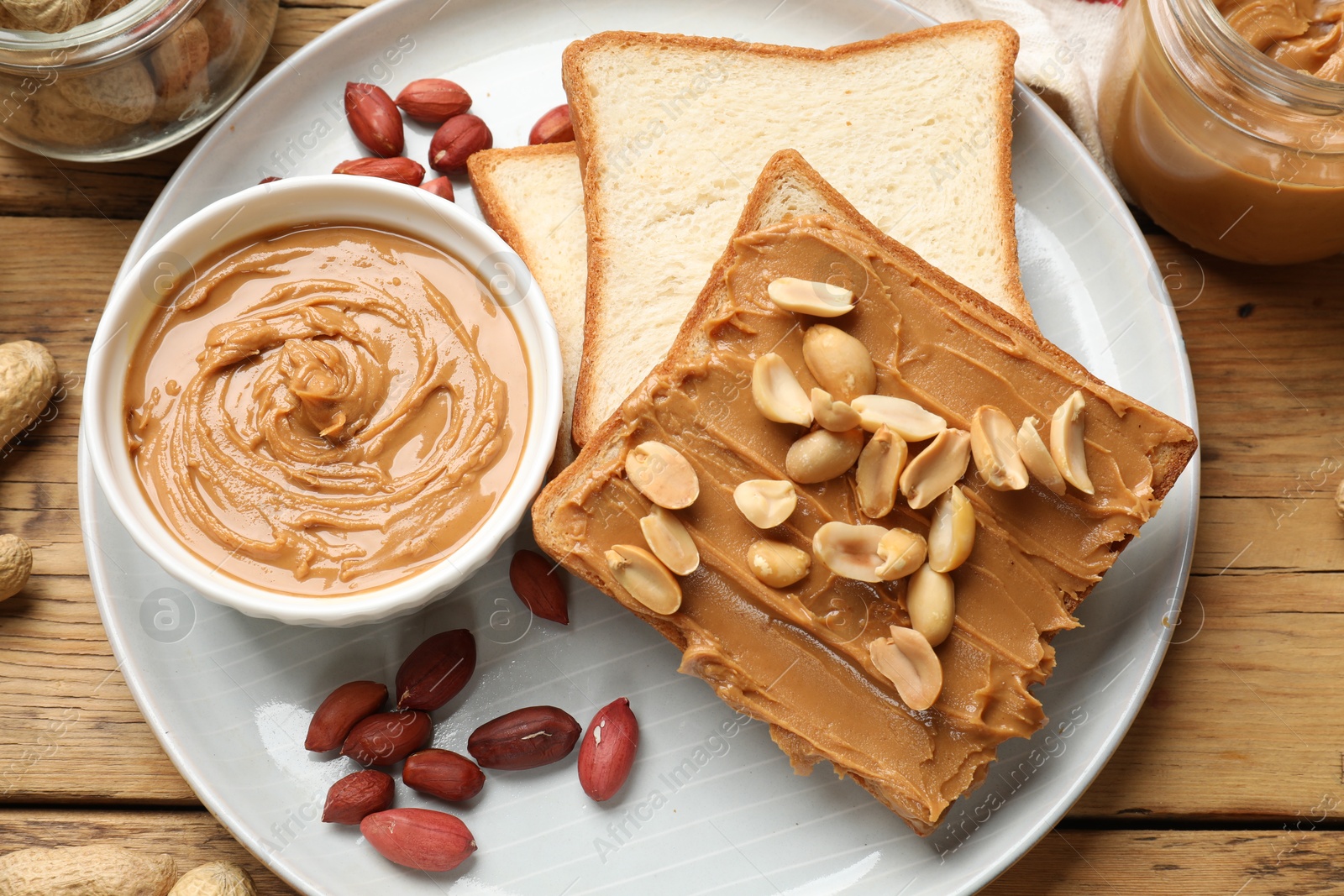 Photo of Delicious sandwich with peanut butter and fresh nuts on wooden table, flat lay