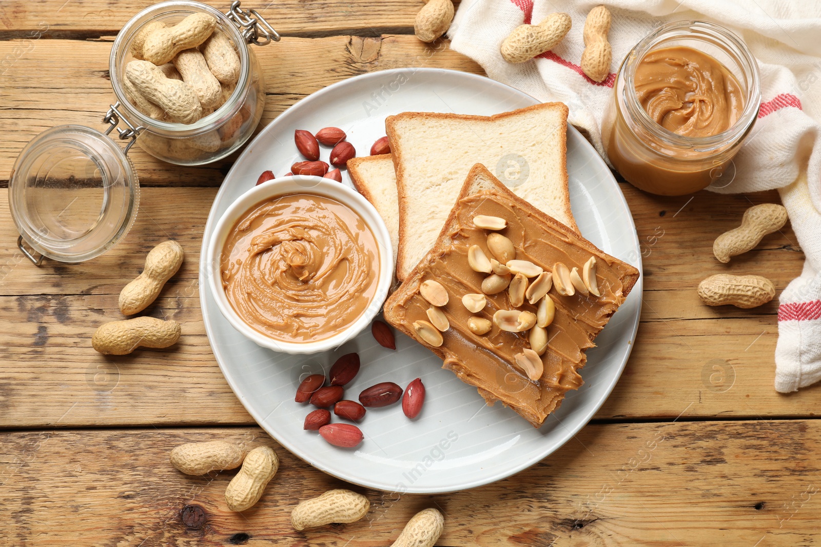 Photo of Delicious sandwich with peanut butter and fresh nuts on wooden table, flat lay