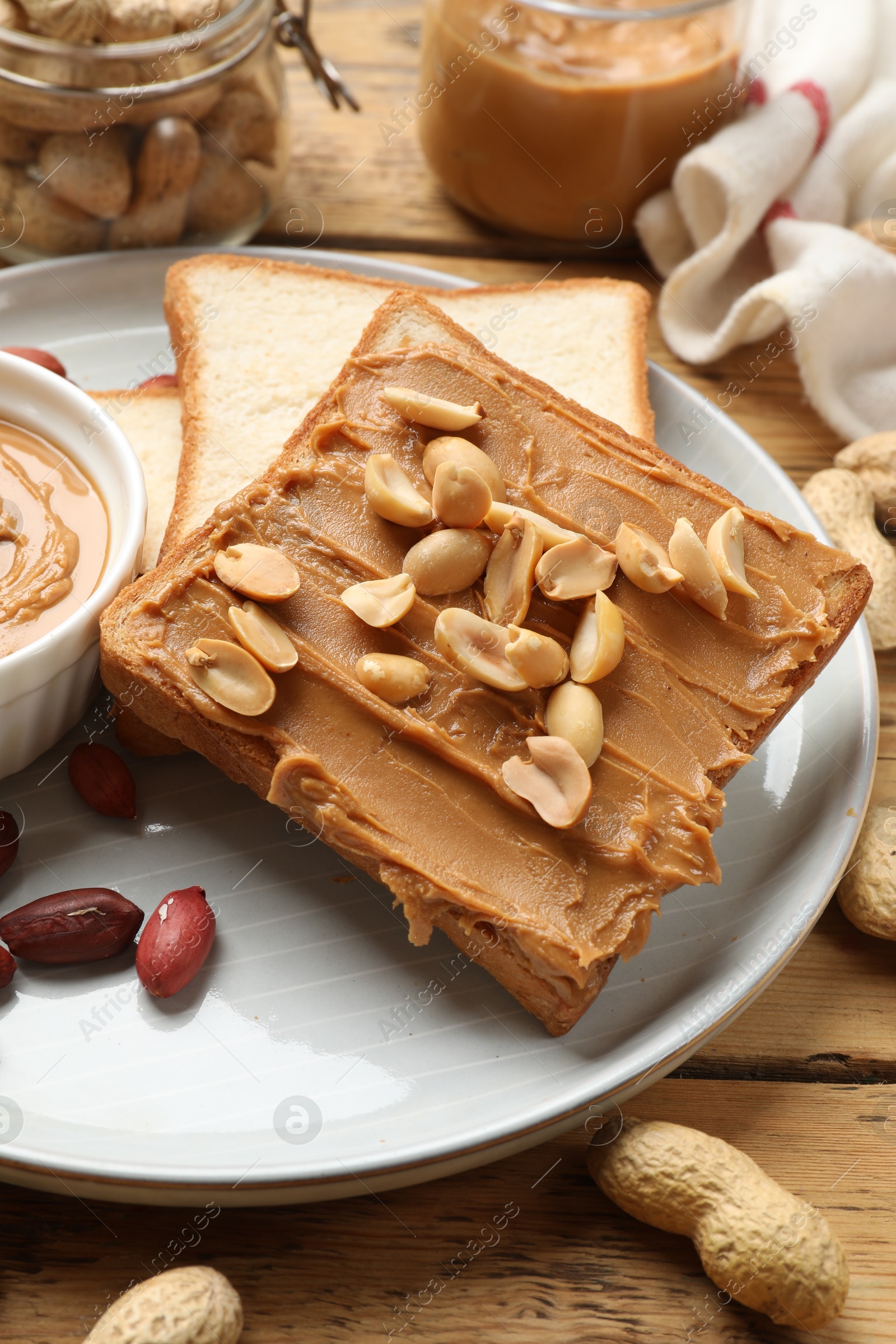 Photo of Delicious sandwich with peanut butter and fresh nuts on wooden table, closeup