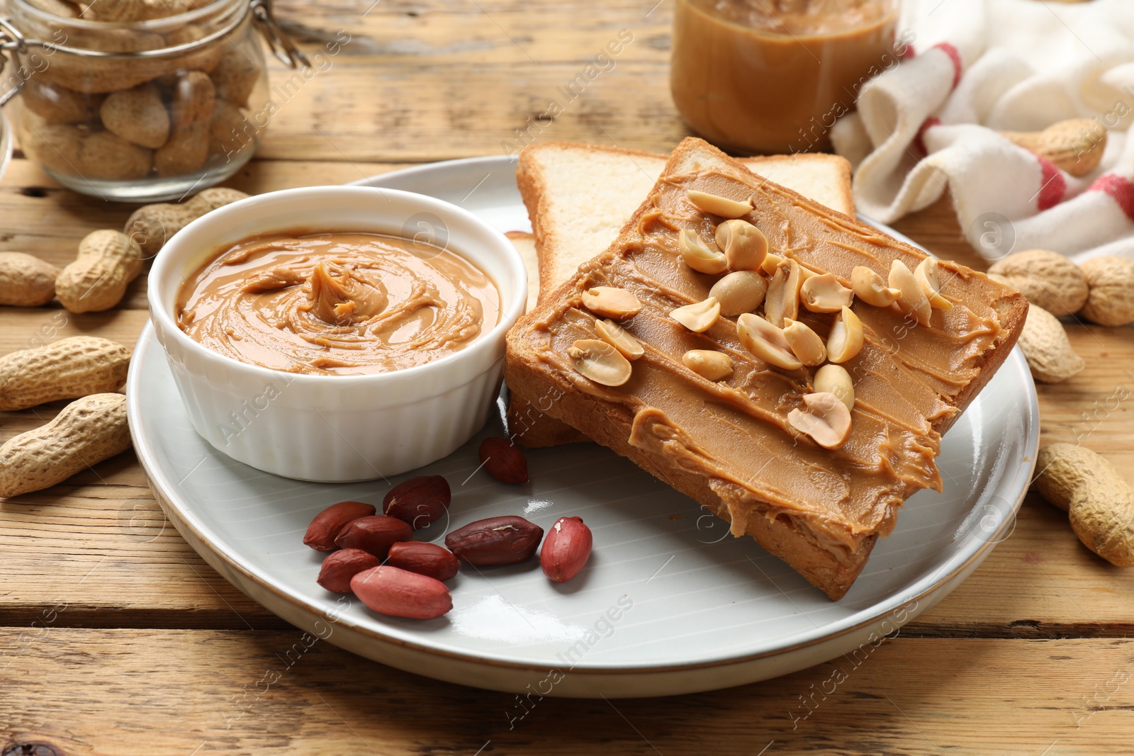 Photo of Delicious sandwich with peanut butter and fresh nuts on wooden table, closeup