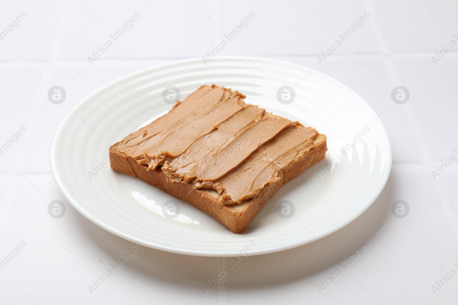 Photo of Delicious sandwich with peanut butter on white tiled table, closeup