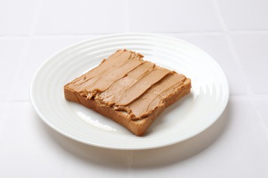 Photo of Delicious sandwich with peanut butter on white tiled table, closeup