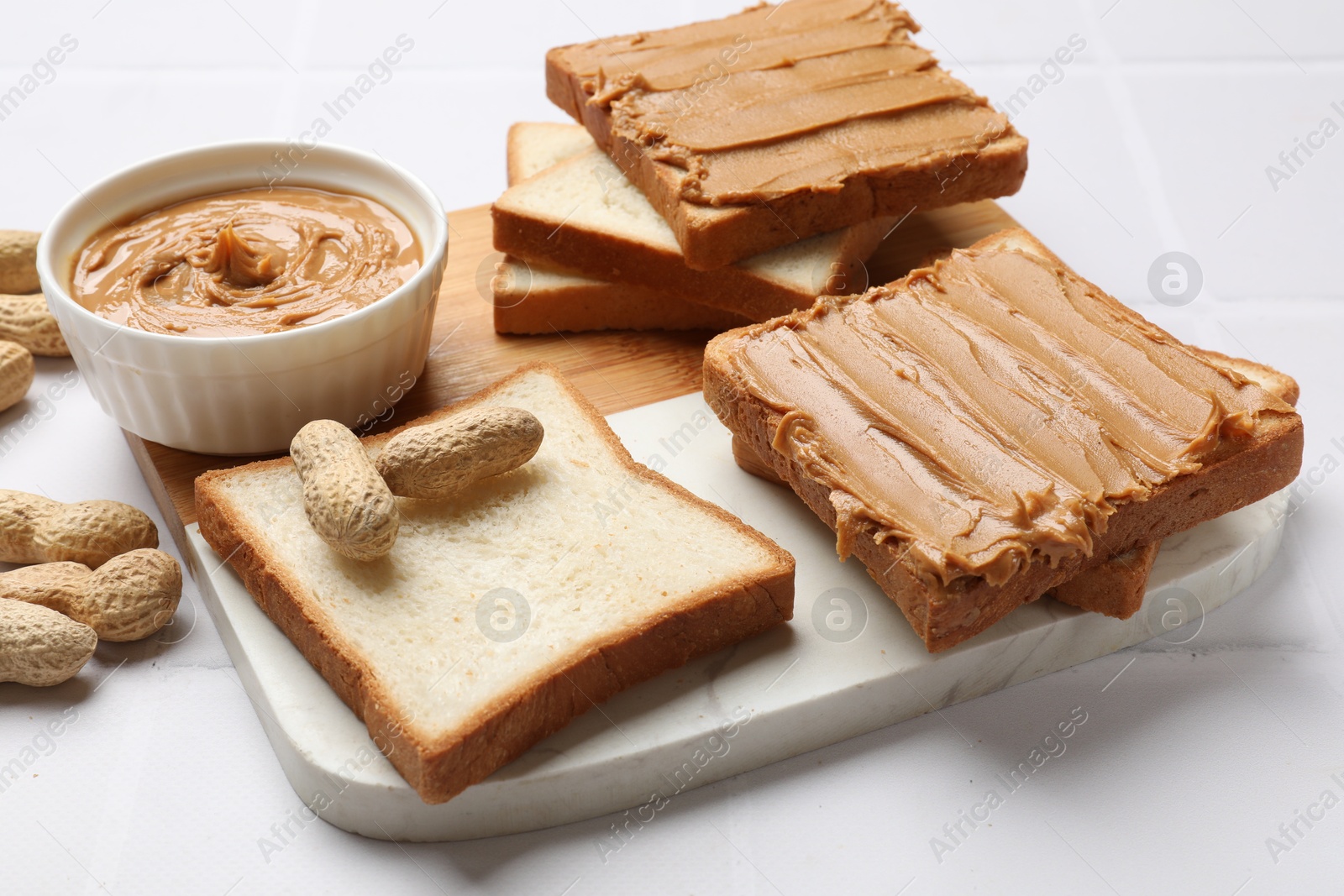 Photo of Delicious sandwiches with peanut butter and fresh nuts on white table, closeup