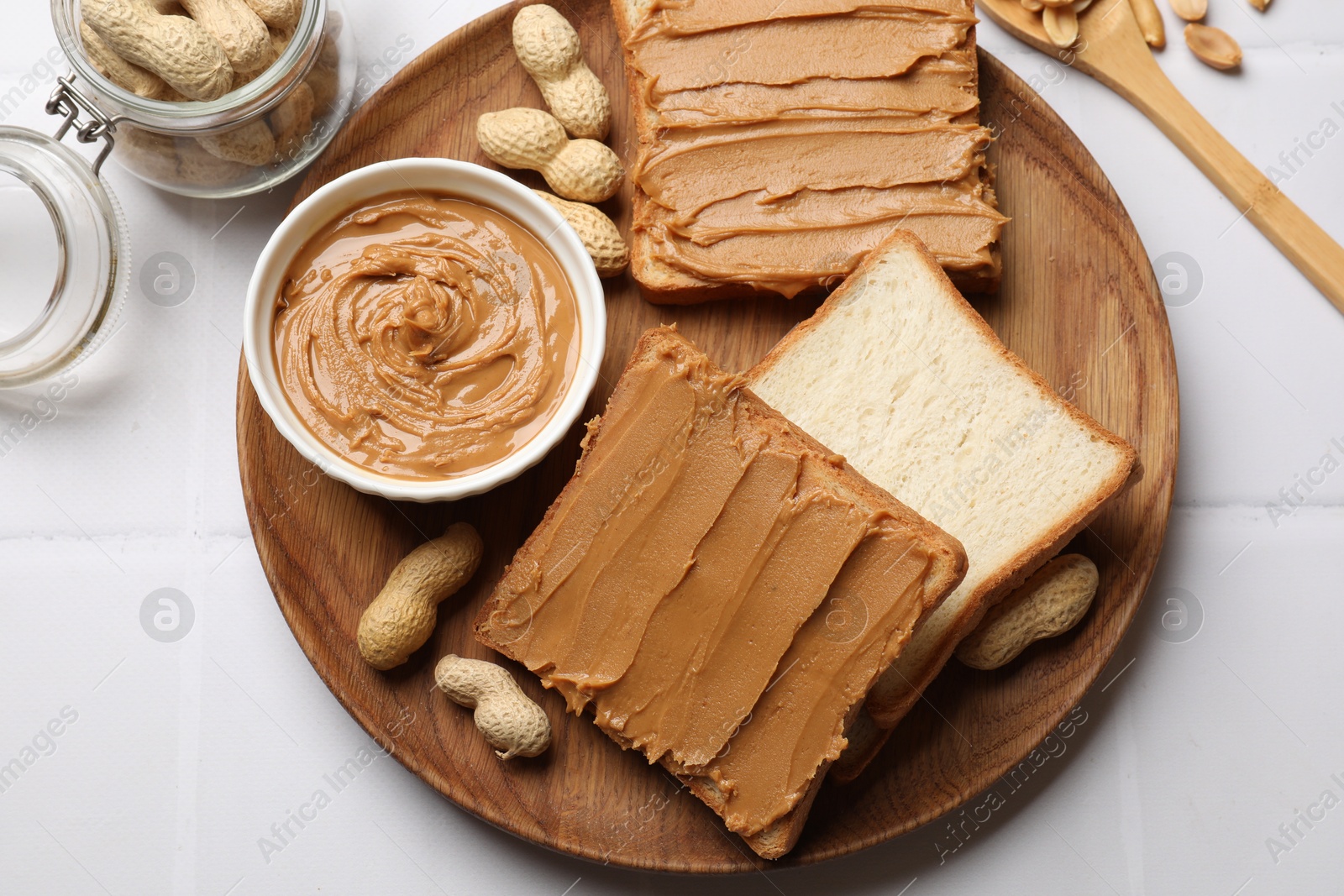 Photo of Delicious sandwiches with peanut butter and fresh nuts on white table, flat lay