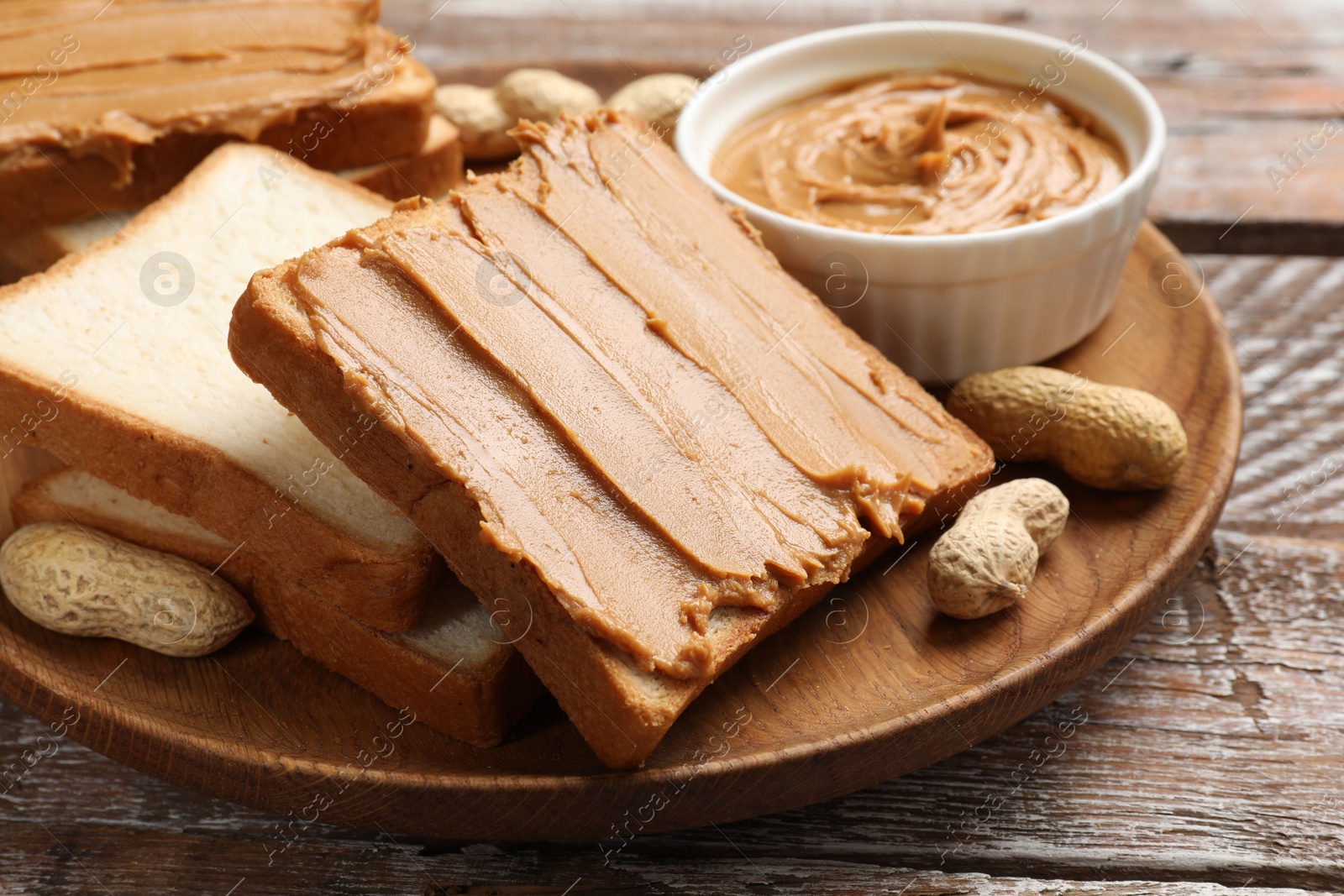 Photo of Delicious sandwiches with peanut butter and fresh nuts on wooden table, closeup