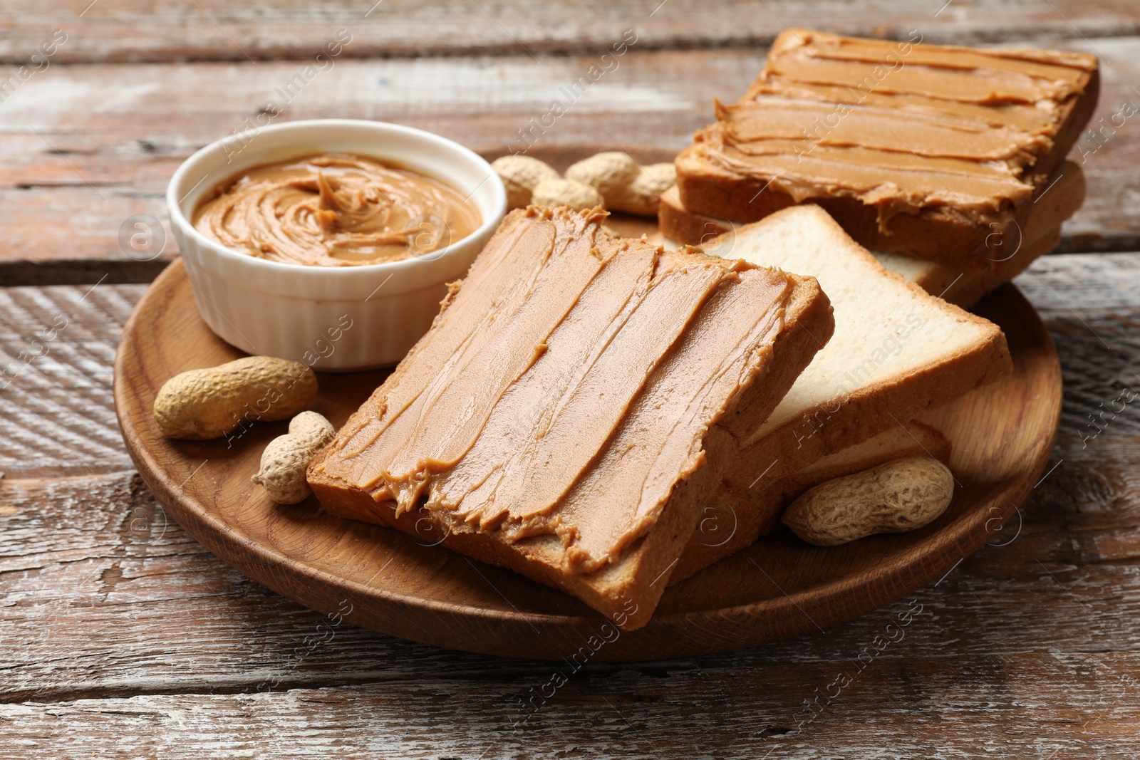 Photo of Delicious sandwiches with peanut butter and fresh nuts on wooden table, closeup