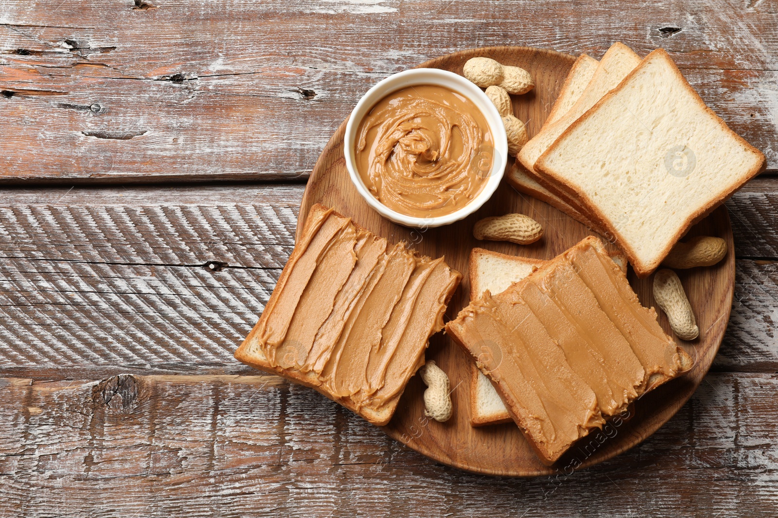 Photo of Delicious sandwiches with peanut butter and fresh nuts on wooden table, top view. Space for text