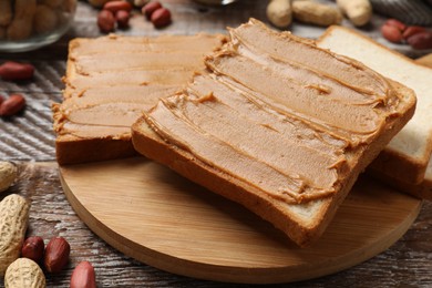 Delicious sandwiches with peanut butter and fresh nuts on wooden table, closeup