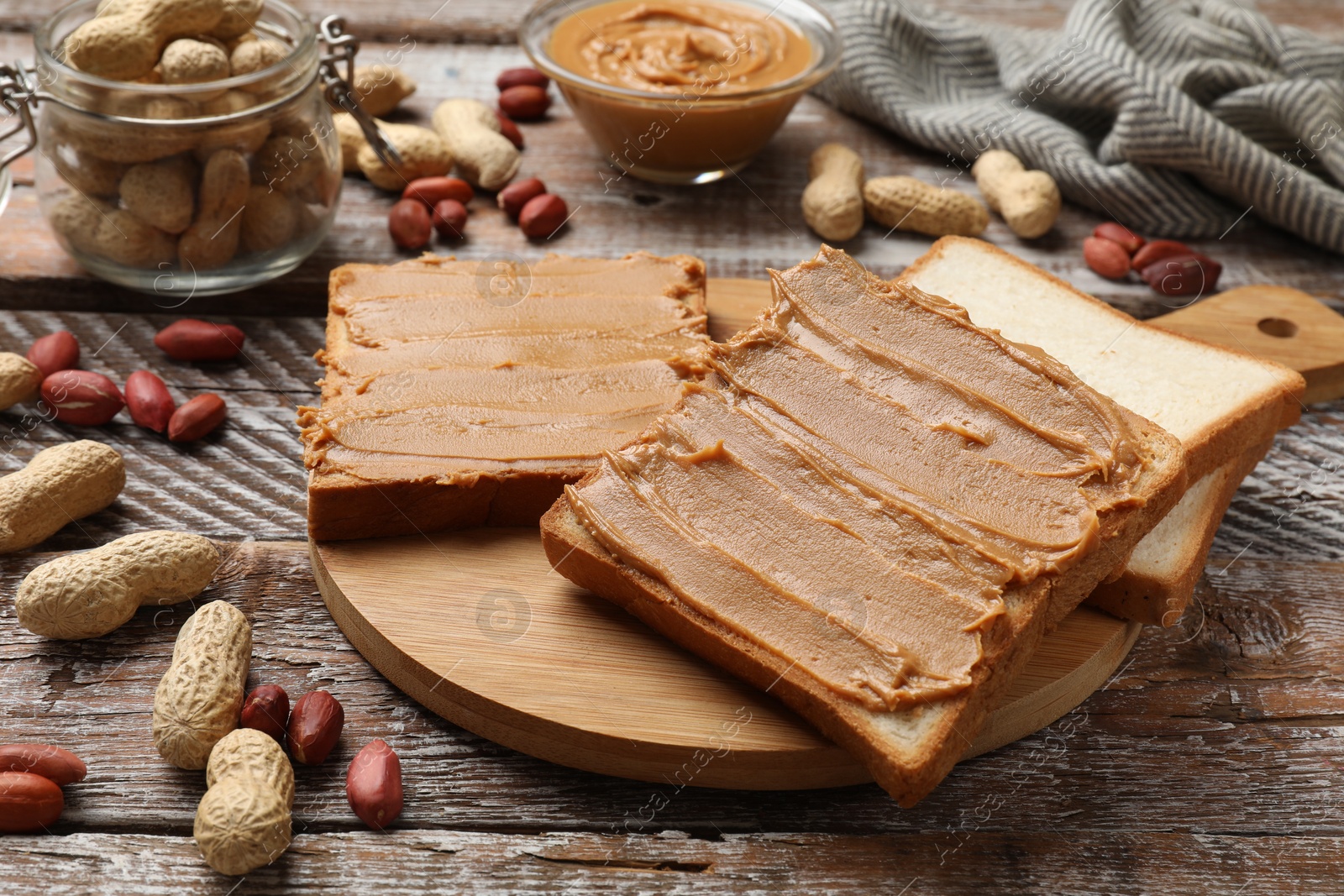 Photo of Delicious sandwiches with peanut butter and fresh nuts on wooden table, closeup