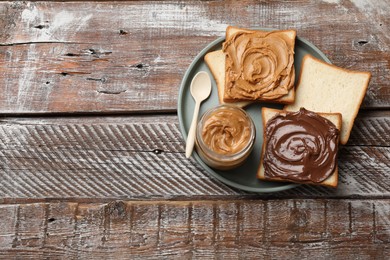 Photo of Delicious sandwiches with peanut butter and chocolate paste on wooden table, top view. Space for text